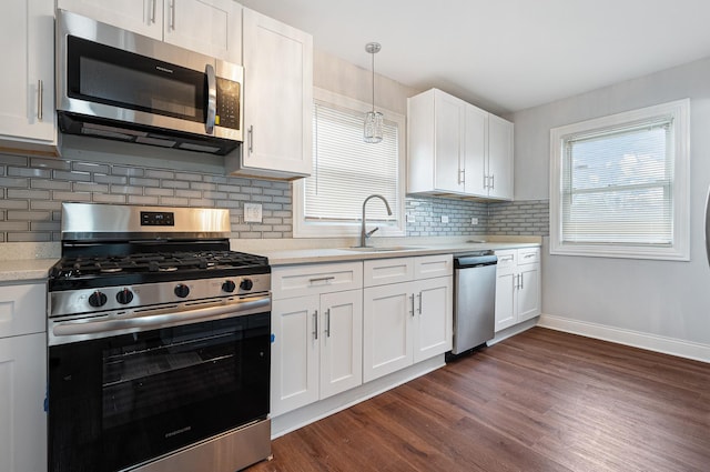 kitchen featuring stainless steel appliances, white cabinetry, hanging light fixtures, and sink