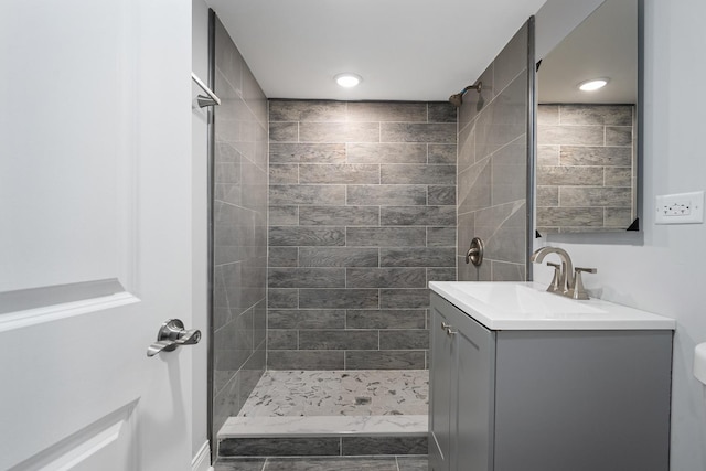 bathroom with a tile shower, vanity, and toilet