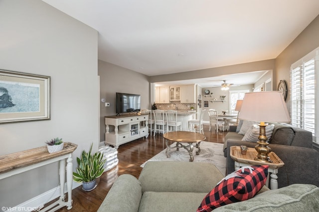 living room featuring ceiling fan and dark wood-type flooring