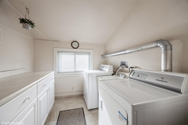 clothes washing area with washing machine and dryer, light tile patterned floors, and cabinets