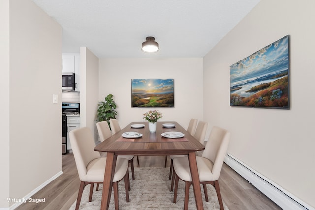 dining area featuring a baseboard radiator and light wood-type flooring