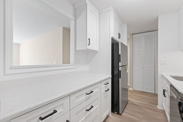 kitchen with white cabinetry, light hardwood / wood-style flooring, a textured ceiling, and appliances with stainless steel finishes