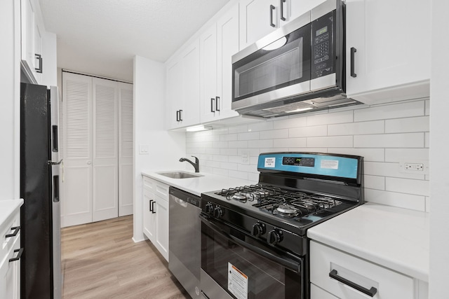 kitchen featuring decorative backsplash, stainless steel appliances, sink, light hardwood / wood-style flooring, and white cabinetry