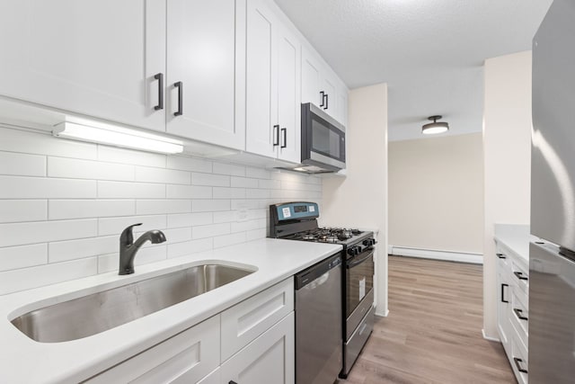 kitchen with white cabinetry, sink, light wood-type flooring, and appliances with stainless steel finishes