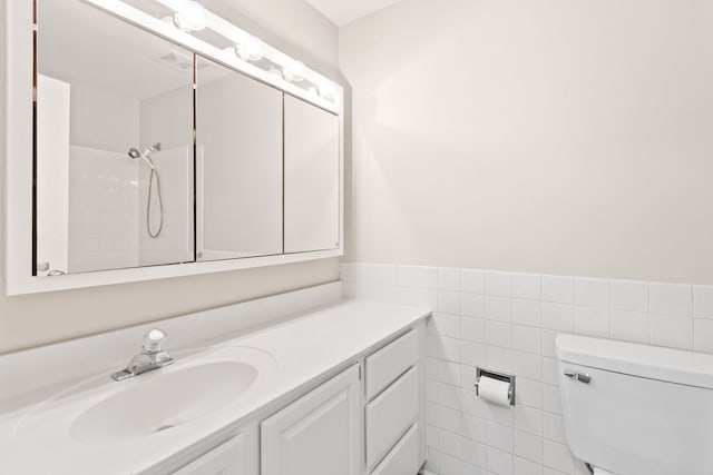 bathroom featuring vanity, toilet, tile walls, and walk in shower