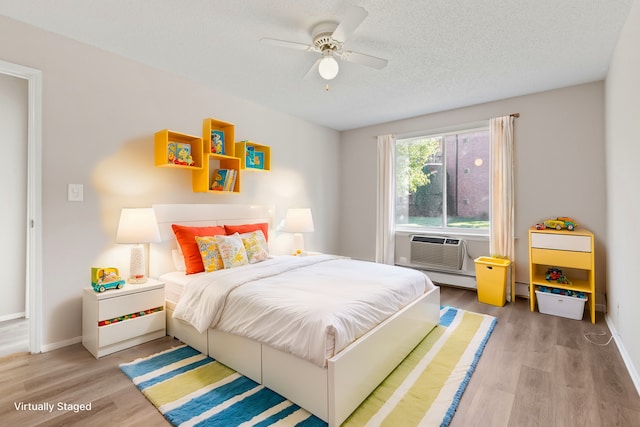 bedroom with ceiling fan, light hardwood / wood-style floors, and a textured ceiling