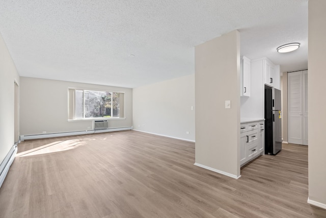 unfurnished living room with baseboard heating, light hardwood / wood-style floors, and a textured ceiling