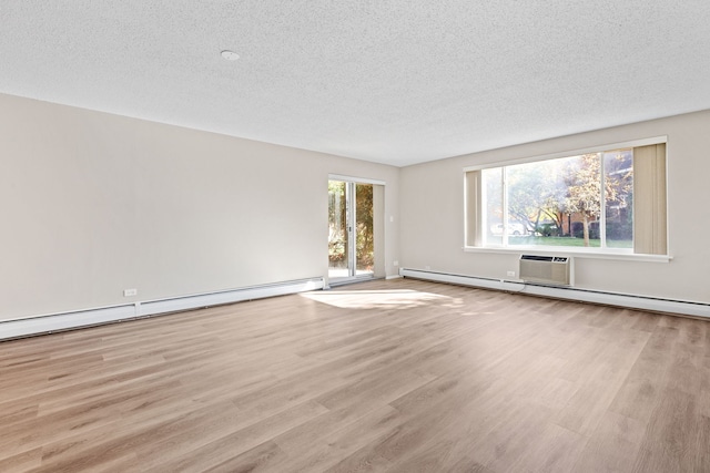 empty room with a wall mounted AC, a baseboard radiator, light hardwood / wood-style floors, and a textured ceiling