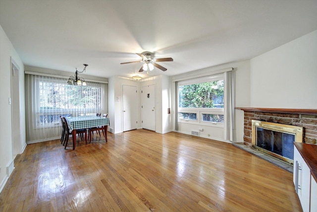 unfurnished living room with plenty of natural light, light hardwood / wood-style floors, and a brick fireplace