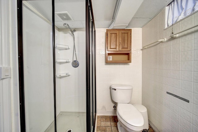 bathroom with toilet, a shower, and tile walls