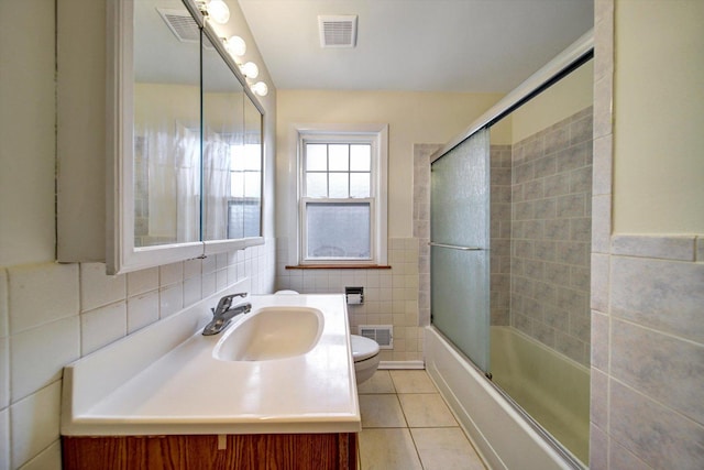 full bathroom featuring tile patterned floors, toilet, enclosed tub / shower combo, and tile walls