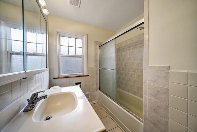 bathroom featuring tile patterned floors, vanity, tile walls, and combined bath / shower with glass door