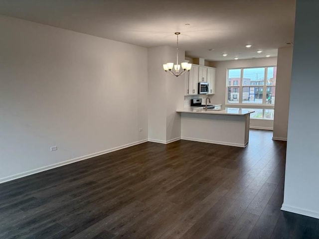 kitchen featuring white cabinetry, dark wood-type flooring, stainless steel appliances, kitchen peninsula, and decorative light fixtures