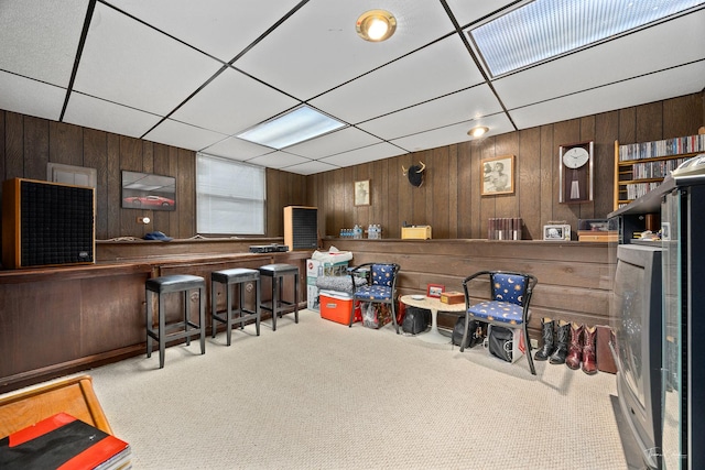 bar with a paneled ceiling, wood walls, and light carpet