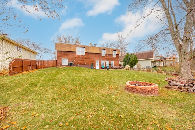 rear view of house featuring a fire pit and a lawn