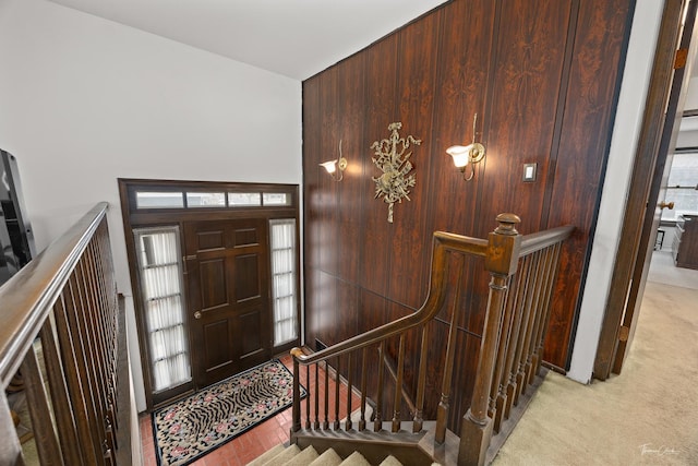 carpeted foyer with wooden walls