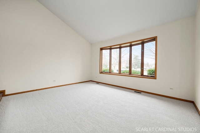 spare room featuring carpet flooring and lofted ceiling