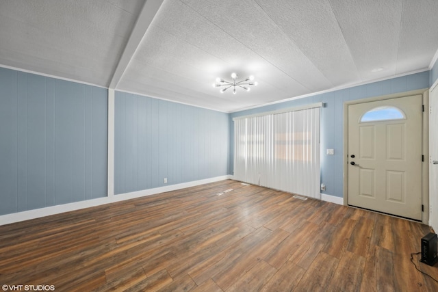 foyer entrance with wooden walls, dark hardwood / wood-style flooring, and a textured ceiling