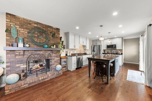 kitchen featuring a kitchen bar, backsplash, decorative light fixtures, and appliances with stainless steel finishes