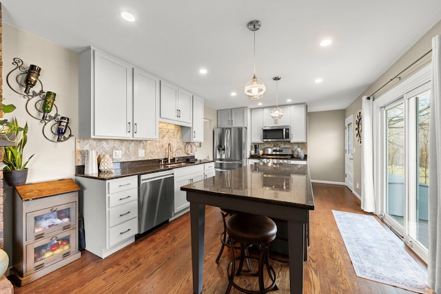 kitchen with appliances with stainless steel finishes, dark hardwood / wood-style flooring, a breakfast bar, a kitchen island, and white cabinetry