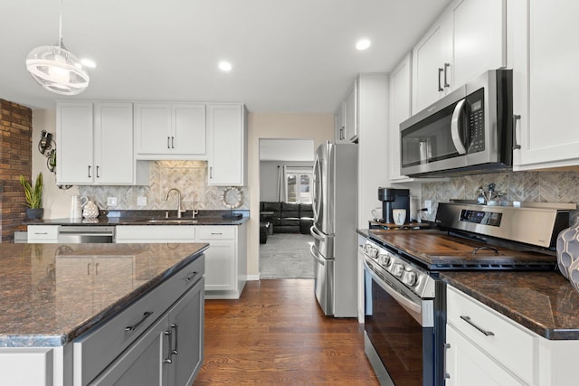 kitchen with hanging light fixtures, sink, decorative backsplash, appliances with stainless steel finishes, and white cabinetry