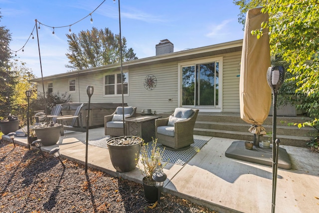 back of house featuring outdoor lounge area, a patio, and a hot tub