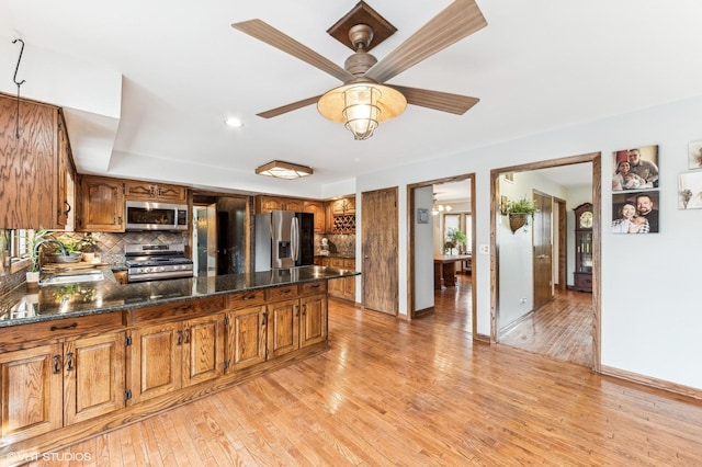 kitchen with brown cabinets, light wood finished floors, stainless steel appliances, tasteful backsplash, and a sink