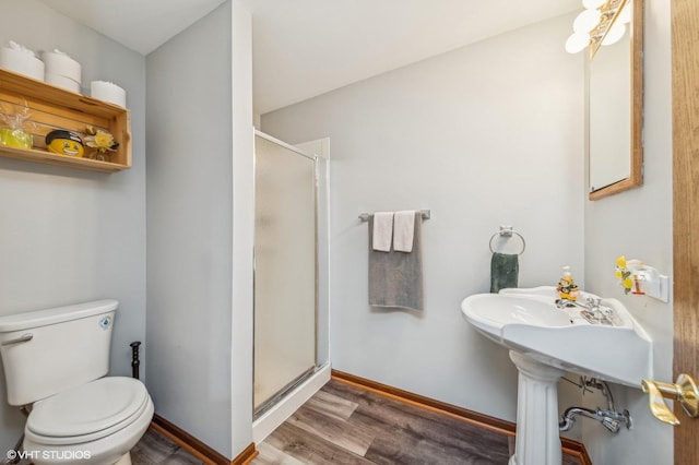 full bath with toilet, a shower stall, baseboards, and wood finished floors