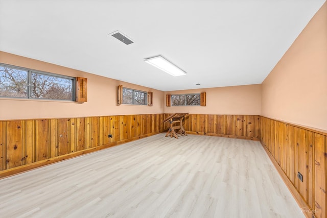 empty room with wood walls and light wood-type flooring