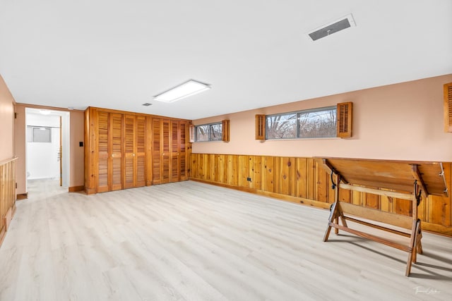 additional living space with wood walls and light hardwood / wood-style floors