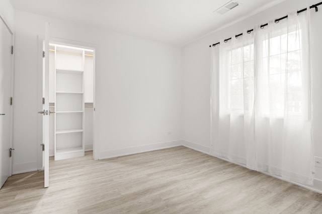 unfurnished bedroom with a walk in closet, light wood-type flooring, and a closet