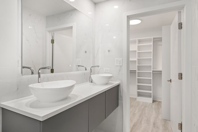 bathroom with hardwood / wood-style floors, vanity, and tile walls