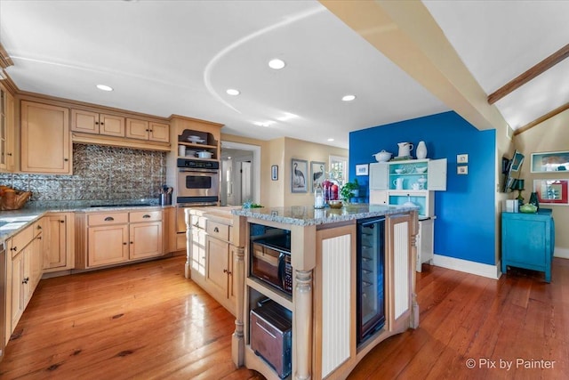 kitchen with light stone countertops, light wood-type flooring, black appliances, light brown cabinets, and a center island