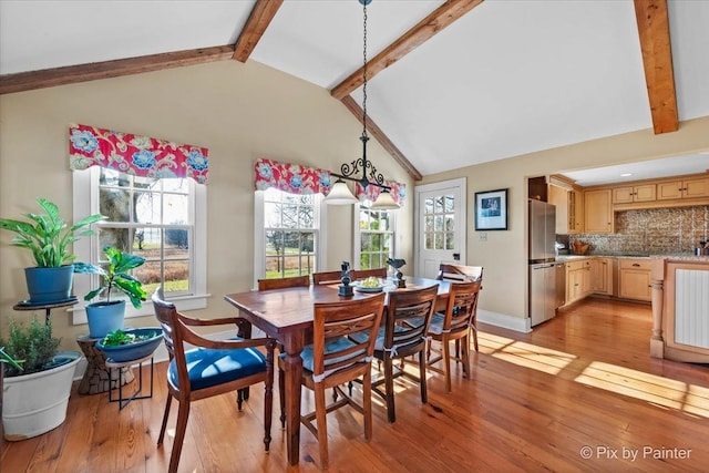 dining space with beamed ceiling, high vaulted ceiling, and light hardwood / wood-style flooring