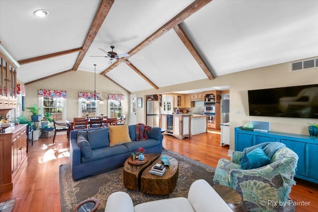 living room with beam ceiling, ceiling fan, beverage cooler, and light wood-type flooring