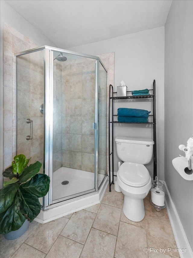 bathroom with tile patterned flooring, toilet, and a shower with door