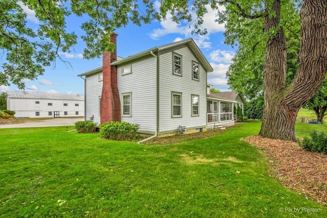 rear view of property with a lawn and a sunroom