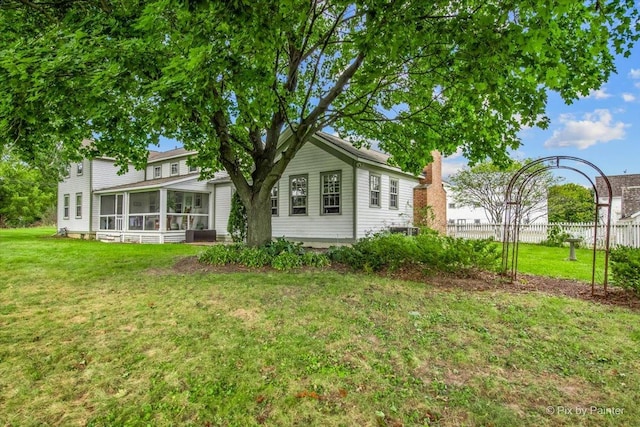 rear view of property featuring a lawn and a sunroom