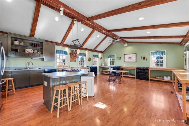 kitchen with lofted ceiling with beams, a kitchen island, a kitchen breakfast bar, and light hardwood / wood-style floors