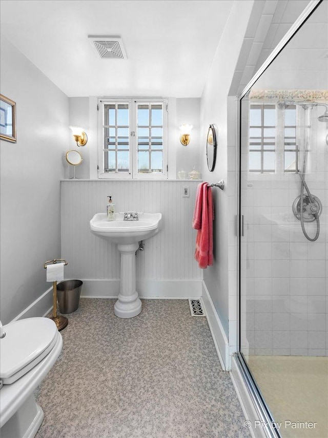 bathroom featuring toilet and a shower with door