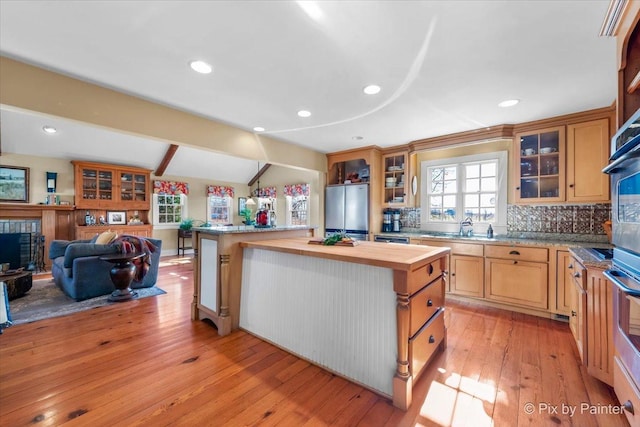 kitchen with wooden counters, tasteful backsplash, stainless steel appliances, light hardwood / wood-style floors, and a kitchen island