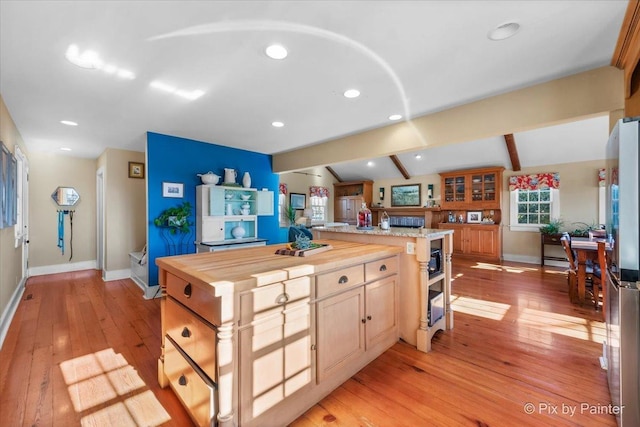 kitchen featuring stainless steel fridge, light brown cabinets, lofted ceiling with beams, light hardwood / wood-style floors, and butcher block counters