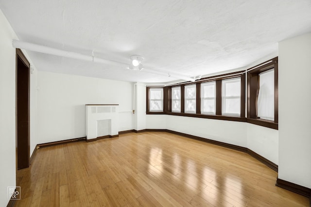 spare room with a textured ceiling and light hardwood / wood-style flooring