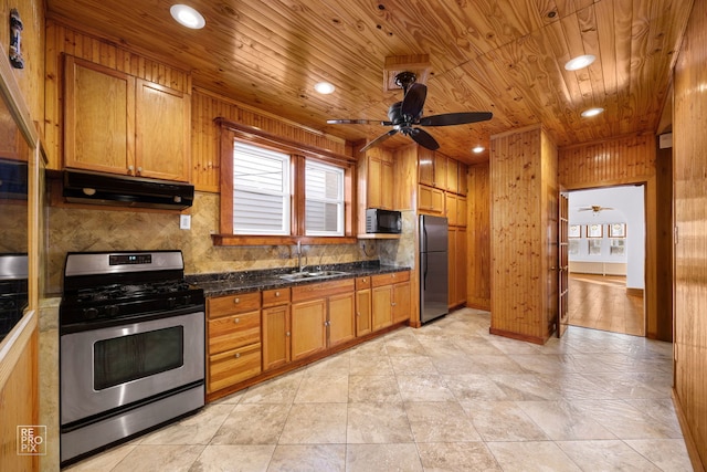 kitchen featuring tasteful backsplash, wooden walls, sink, and stainless steel appliances