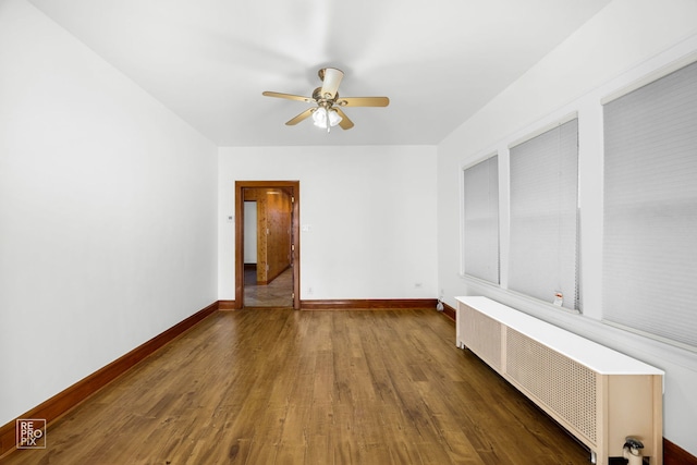 spare room featuring ceiling fan, dark wood-type flooring, and radiator