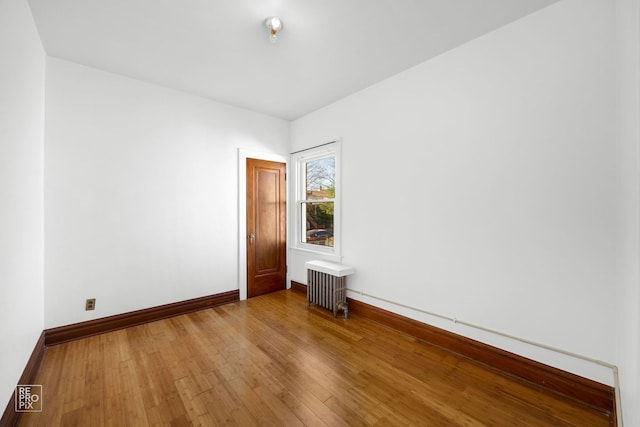 unfurnished room featuring radiator and hardwood / wood-style floors