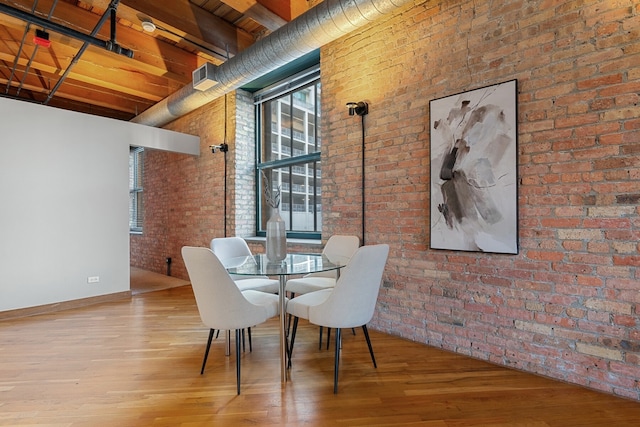 dining space featuring wood-type flooring and a towering ceiling