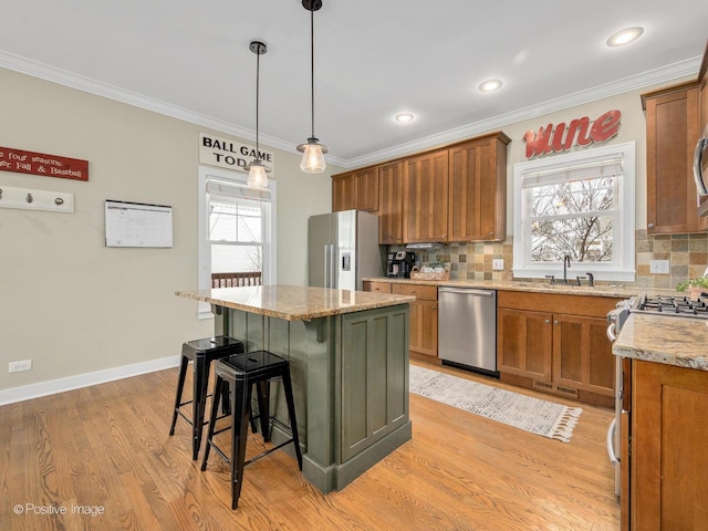 kitchen featuring a breakfast bar area, appliances with stainless steel finishes, hanging light fixtures, light wood-type flooring, and a center island