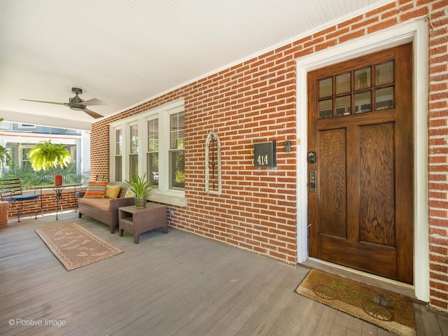 entrance to property featuring covered porch, ceiling fan, and an outdoor living space