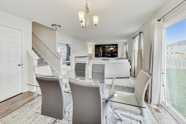 dining space with light hardwood / wood-style flooring, plenty of natural light, and a notable chandelier